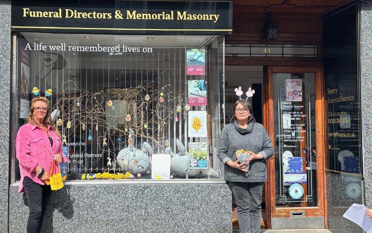 Two ladies with Easter Egg headbands standing in front of the branch.